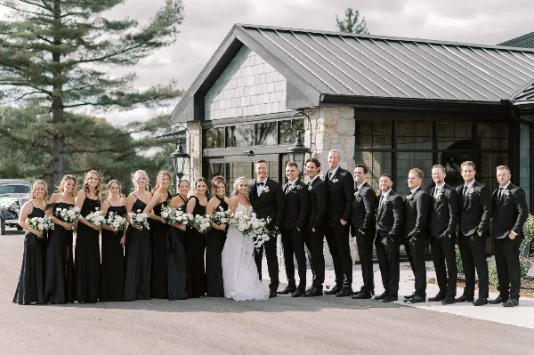 A wedding party posing in front of The Clubhouse venue building.