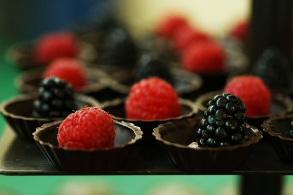 A tray of chocolate cups topped with fresh raspberries and blackberries.