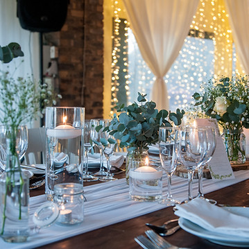 A close-up view of a formal dining table setting featuring glassware, candles, and floral arrangements.