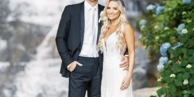 A bride and groom standing together in front of a cascading waterfall at a wedding venue.