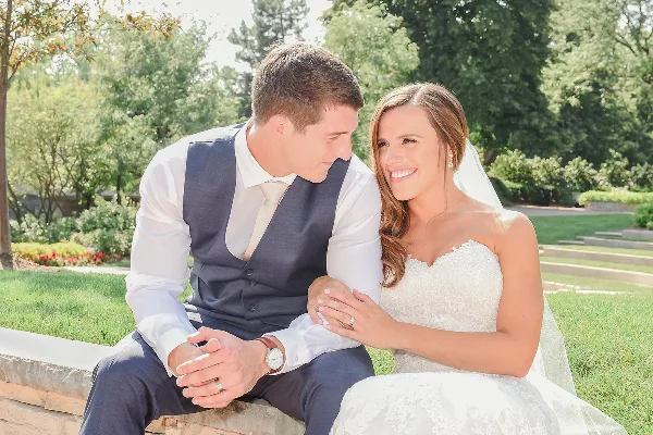 A bride and groom sitting together outdoors in a garden setting.