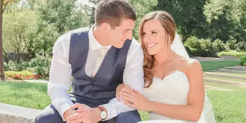A bride and groom sitting together outdoors in a garden setting.