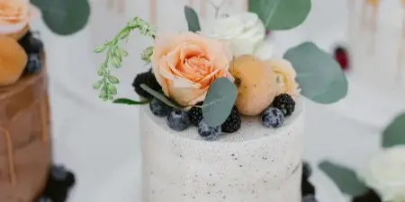 A display of custom cakes decorated with fresh flowers and berries.