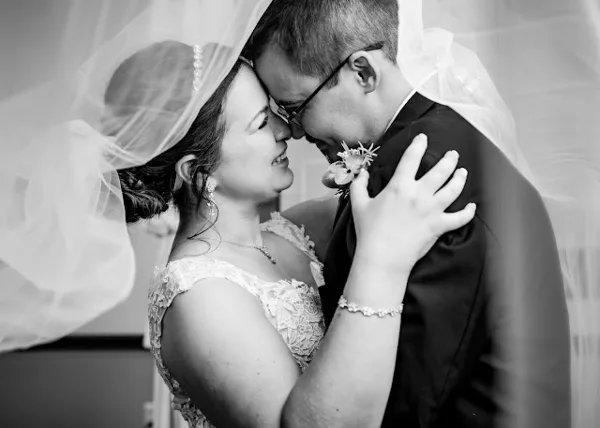 A black and white photograph of a bride and groom embracing and touching foreheads.