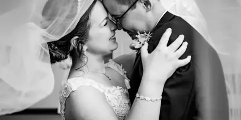 A black and white photograph of a bride and groom embracing and touching foreheads.