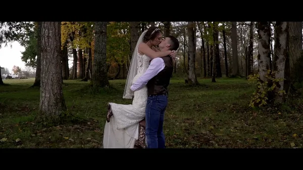 A bride and groom sharing a kiss in a forest setting, captured in a cinematic wedding film style.