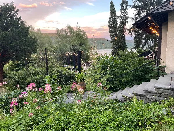 A view of the Brookwood Point lakeside garden venue featuring stone steps, string lights, and a view of the lake and mountains at sunset.