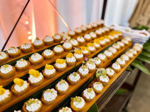 A long wooden platter filled with rows of small, garnished appetizers.