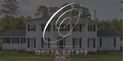 Exterior view of the Ocala Estate historic Southern manor with a white facade, dark shutters, and a front lawn.
