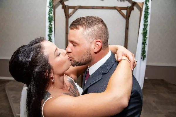 A bride and groom sharing a kiss during a wedding reception.