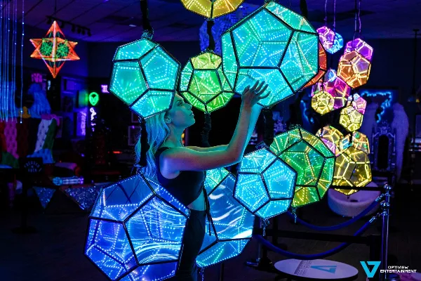 A person interacting with large, illuminated geometric LED art installations inside the OptiView 360 immersive studio.