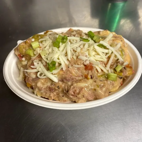 A white bowl filled with creamy mac and cheese topped with shredded cheese and green onions.