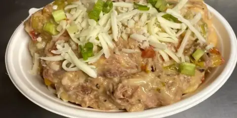 A white bowl filled with creamy mac and cheese topped with shredded cheese and green onions.