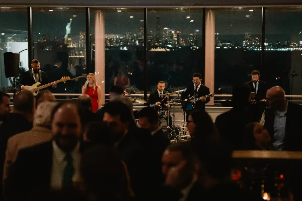 A live band performing at an event with a city skyline visible in the background.