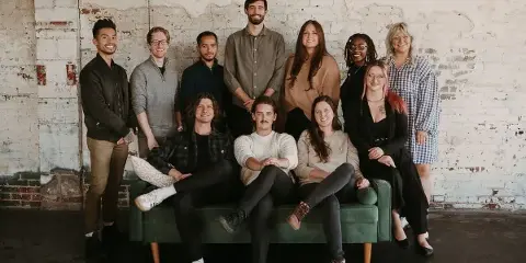 Group photo of the Alumni Productions team members posing in a studio setting.
