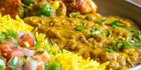 A close-up of a Curry Up Now bowl featuring lentil curry, yellow rice, and roasted vegetables.