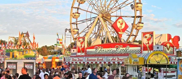 A crowded fairground featuring a large Ferris wheel and a food stand labeled 'Classic Cafe'.