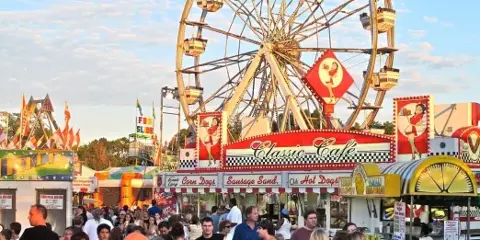 A crowded fairground featuring a large Ferris wheel and a food stand labeled 'Classic Cafe'.