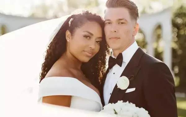 A professional portrait of a bride and groom in formal wedding attire.