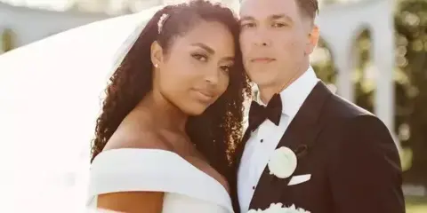 A professional portrait of a bride and groom in formal wedding attire.