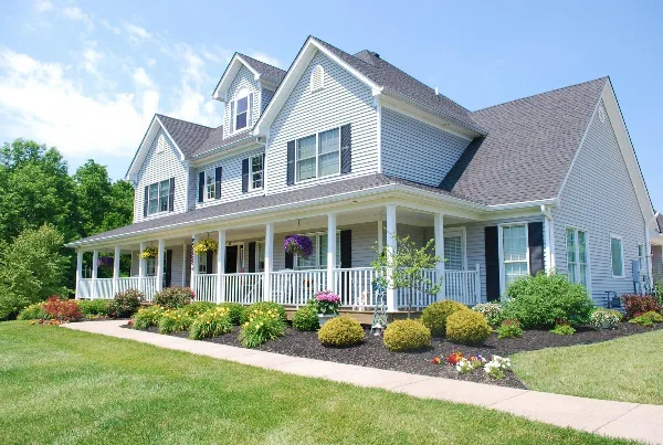 Exterior view of a two-story white house with a porch and landscaped garden.
