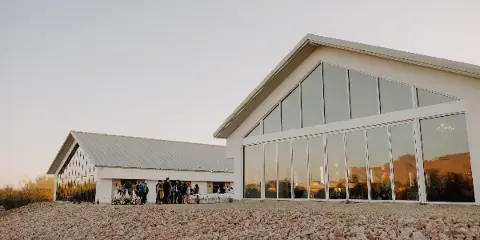 Exterior view of a modern white wedding venue with large glass windows and a gravel foreground.