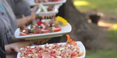 Catering staff serving platters of shrimp and appetizers at an outdoor event