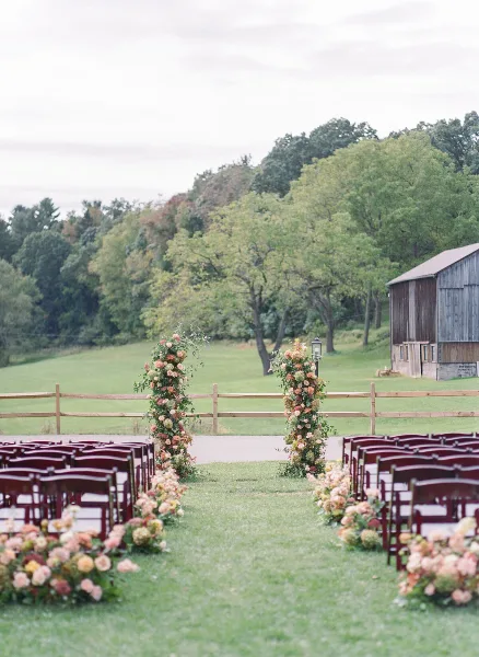 Outdoor wedding ceremony aisle decorated with floral arrangements and markers