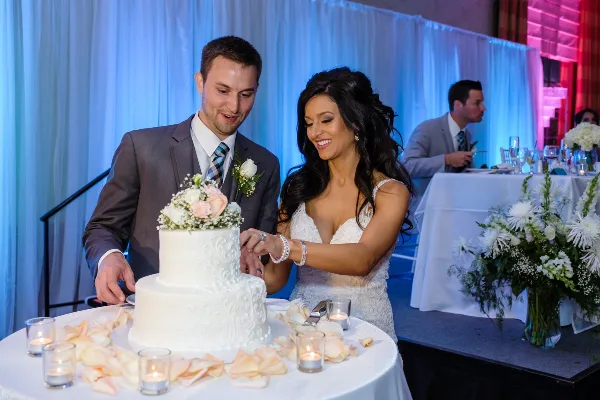 A bride and groom cutting a wedding cake at a reception.