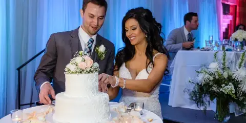 A bride and groom cutting a wedding cake at a reception.