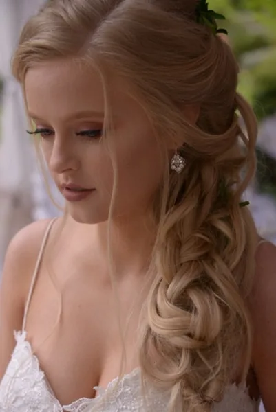 A bride with an elegant, braided updo hairstyle and professional makeup.