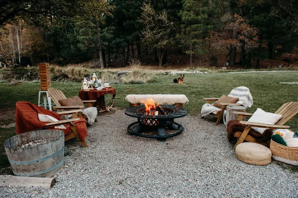 Outdoor fire pit area with wooden lounge chairs and a gravel patio at The Waterfall Lodge.