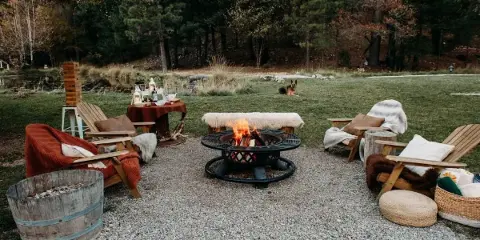 Outdoor fire pit area with wooden lounge chairs and a gravel patio at The Waterfall Lodge.
