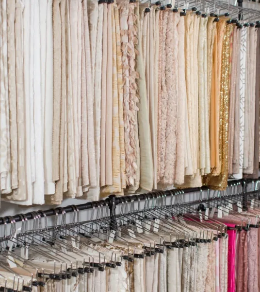 Rows of event linens and table runners hanging on racks in a rental showroom