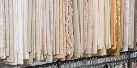 Rows of event linens and table runners hanging on racks in a rental showroom
