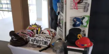 A photo booth station set up with a camera and a rack of party props including hats and glasses.