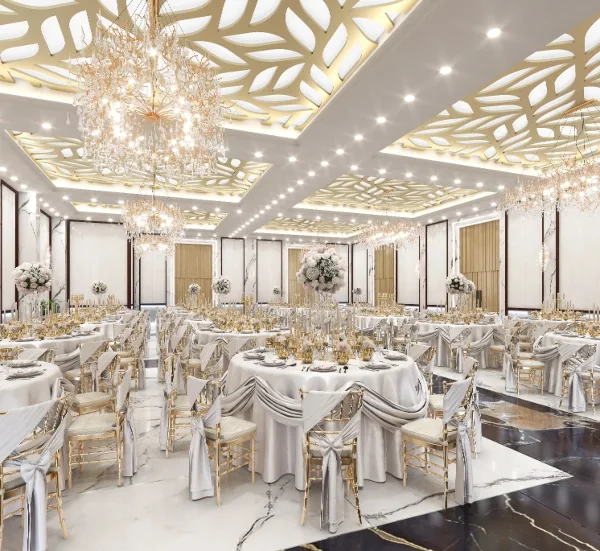 Interior view of a large event hall with round tables, white linens, gold chairs, and ornate chandeliers.
