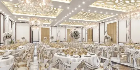 Interior view of a large event hall with round tables, white linens, gold chairs, and ornate chandeliers.