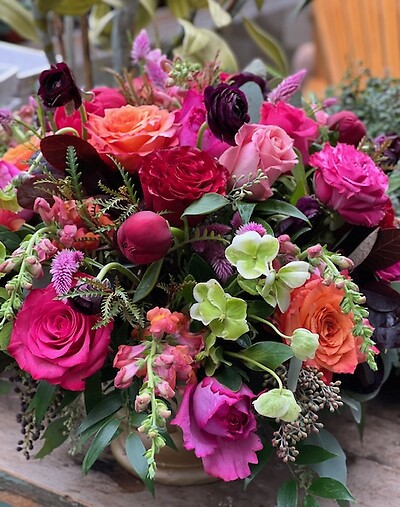 A vibrant floral arrangement featuring pink and orange roses, hydrangeas, and mixed greenery.