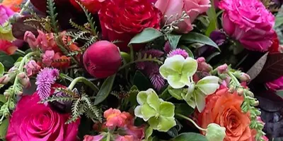 A vibrant floral arrangement featuring pink and orange roses, hydrangeas, and mixed greenery.