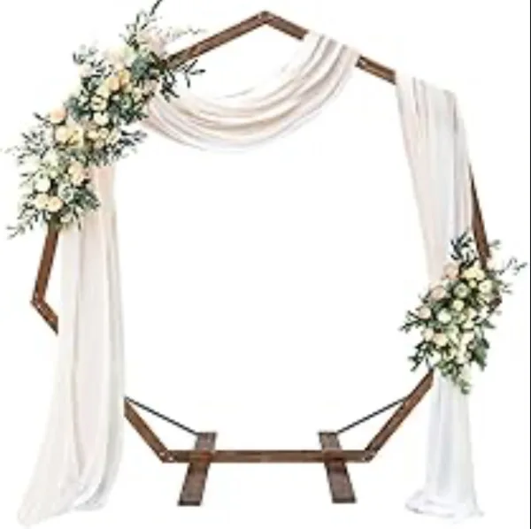 A wooden heptagon wedding arch decorated with white drapery and floral arrangements.