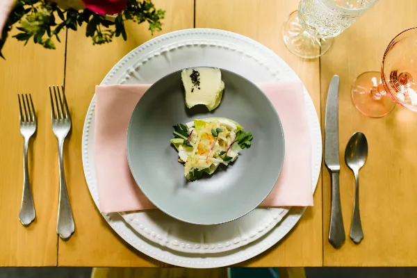 A plated gourmet dish served on a formal table setting with silverware and glassware.