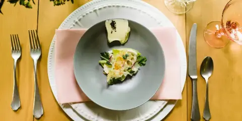 A plated gourmet dish served on a formal table setting with silverware and glassware.