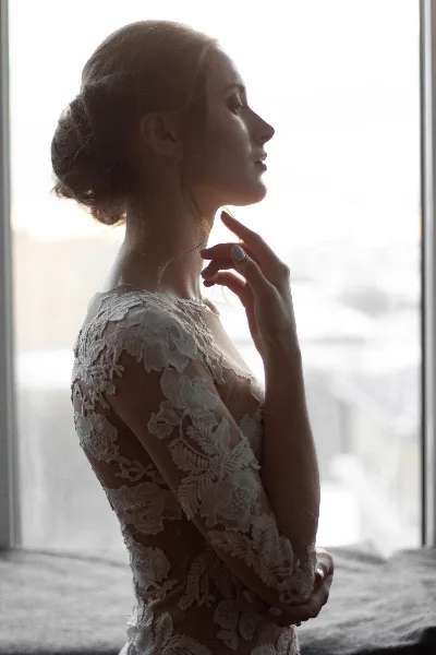 Profile view of a bride wearing a lace wedding dress with a romantic updo hairstyle and natural makeup.