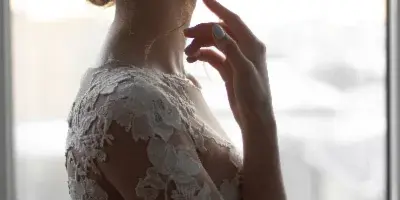 Profile view of a bride wearing a lace wedding dress with a romantic updo hairstyle and natural makeup.