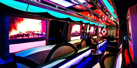 Interior view of a party bus featuring curved seating, colorful LED lighting, and large windows.