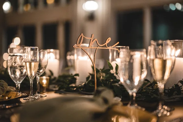 Styled event table setting with candles, glassware, greenery, and a 'one' table number