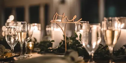 Styled event table setting with candles, glassware, greenery, and a 'one' table number