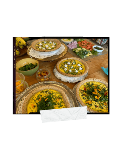 A table filled with various prepared dishes including quiches, salads, and garnishes.