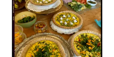 A table filled with various prepared dishes including quiches, salads, and garnishes.